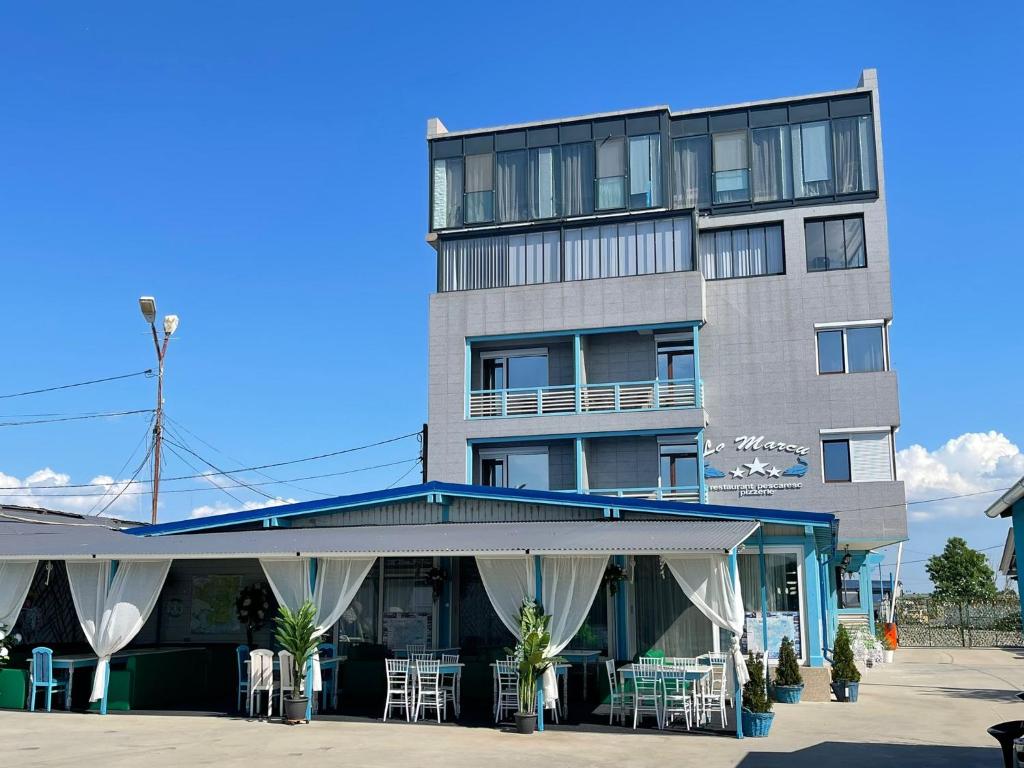 un bâtiment avec des tables et des chaises devant lui dans l'établissement La Marcu Pensiune, à Tulcea