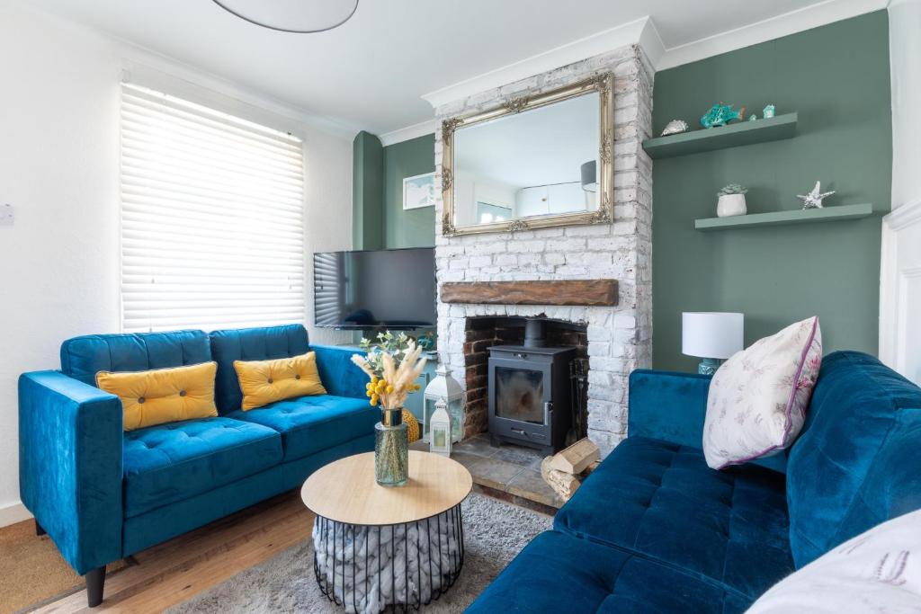 a blue couch in a living room with a fireplace at Sprite Cottage, in the heart of Whitstable in Whitstable