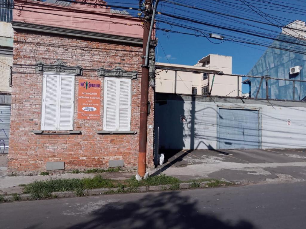 a brick building with white shuttered windows on a street at Trip Adventure Poa in Porto Alegre