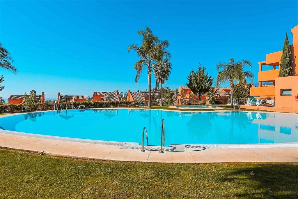una gran piscina con palmeras y un edificio en R25 Modern bright 2 bedroom apartment, en Marbella
