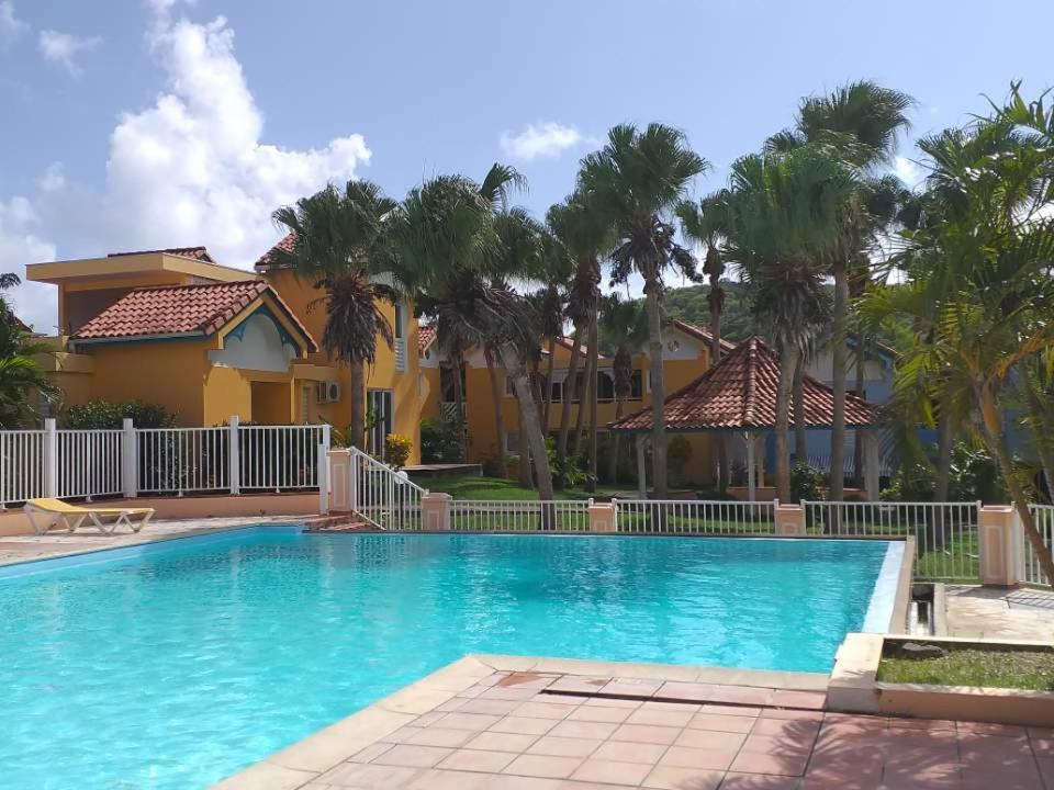 a pool in front of a house with palm trees at Appt 2chb avec piscine in Sainte-Anne