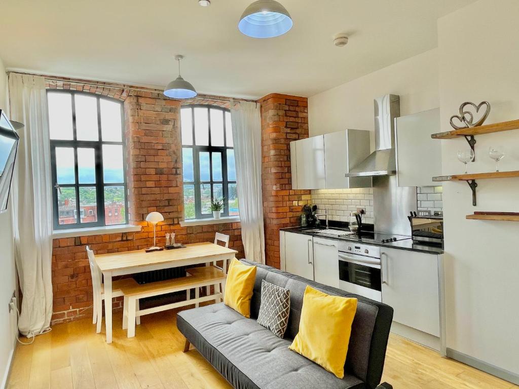 uma cozinha e sala de estar com um sofá e uma mesa em Victorian Factory Apartment with 2 Bedrooms em Bristol