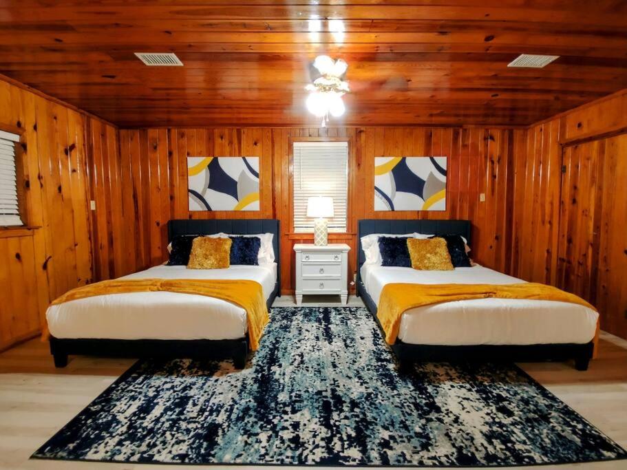 two beds in a room with wood paneled walls at Lake Haven Cottage On Lake Hamilton in Hot Springs