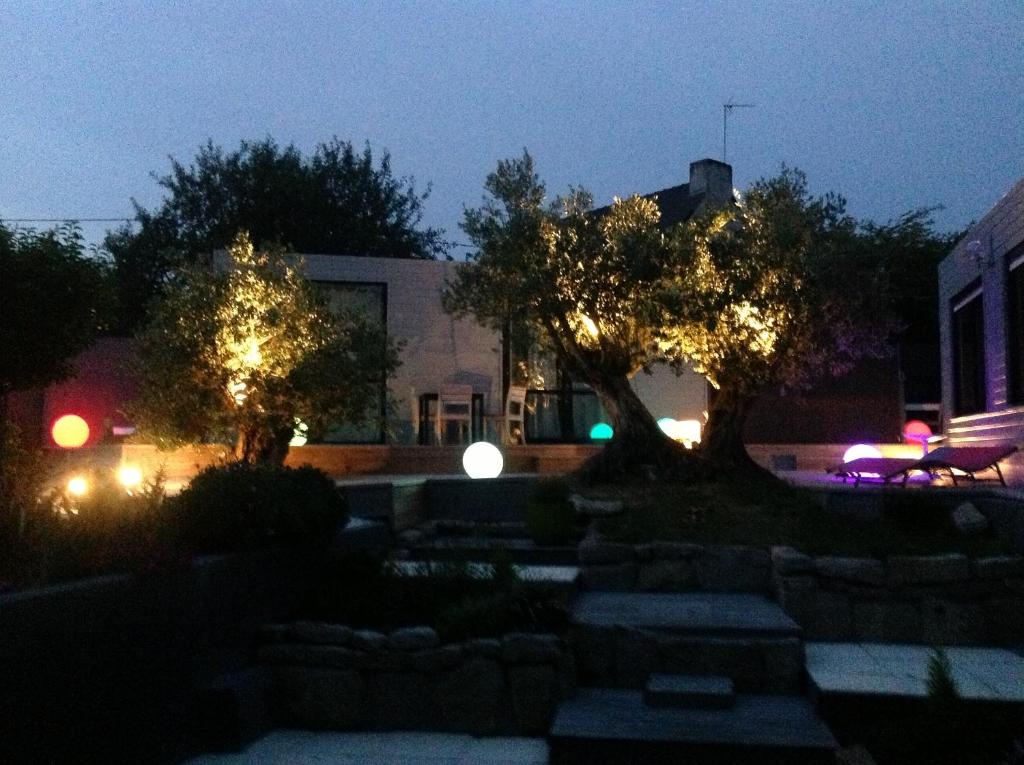 une maison éclairée la nuit avec des arbres et des lumières dans l'établissement les suites de bach, à Ploemeur