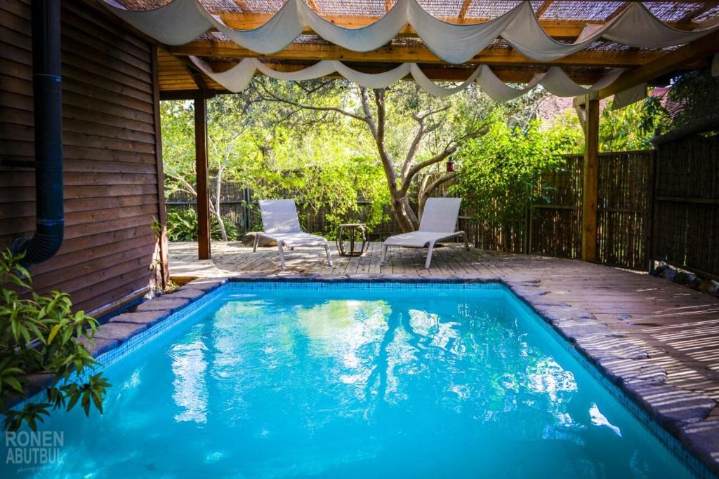 a swimming pool in a backyard with a gazebo at Itamar Cabins in Had Nes