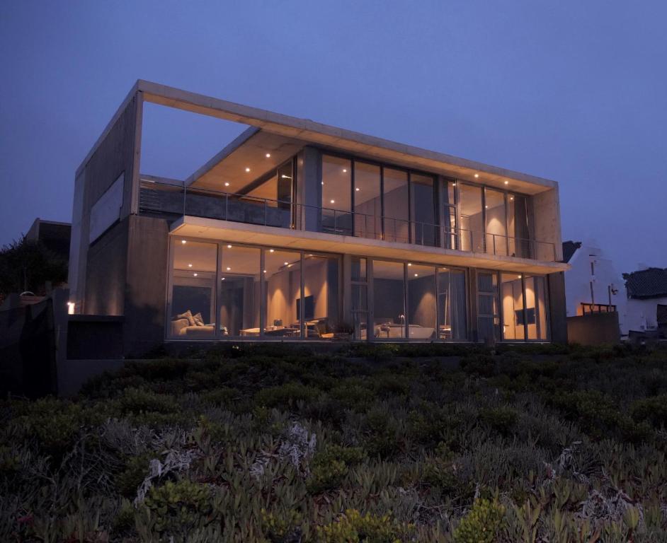 una casa con grandes ventanas de cristal en una colina en The Olive Tree Villa, en Yzerfontein