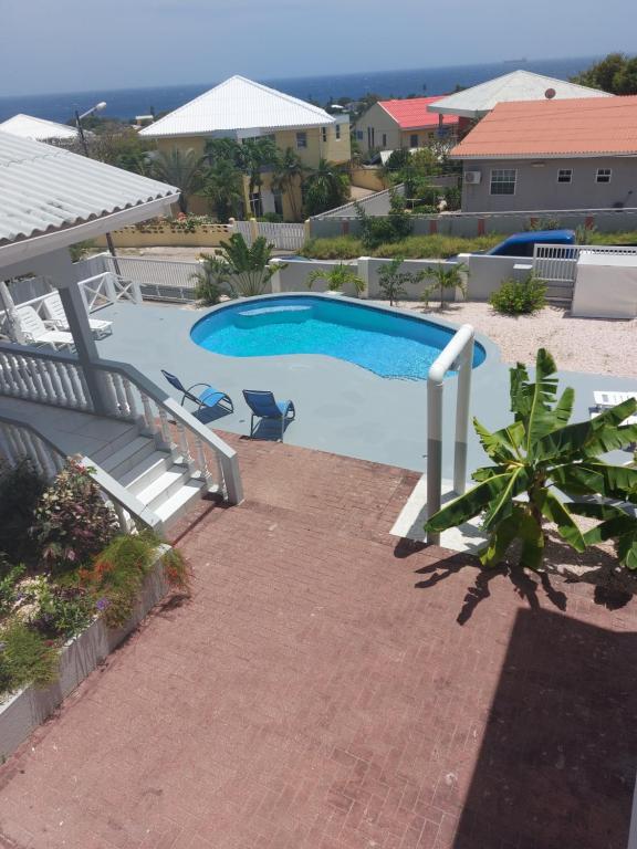 a view of a swimming pool with two chairs and avisor at Villa Raven`s Paradise (Lavender) in Willemstad