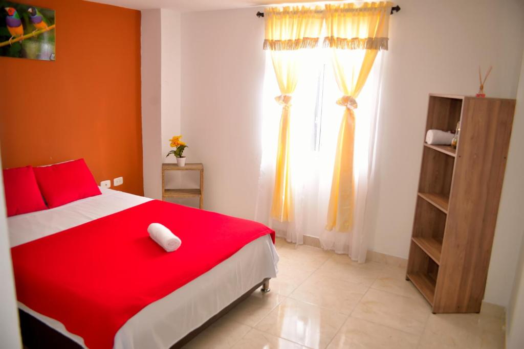a bedroom with a red bed and a window at Hotel Casa Alejandria in Quimbaya