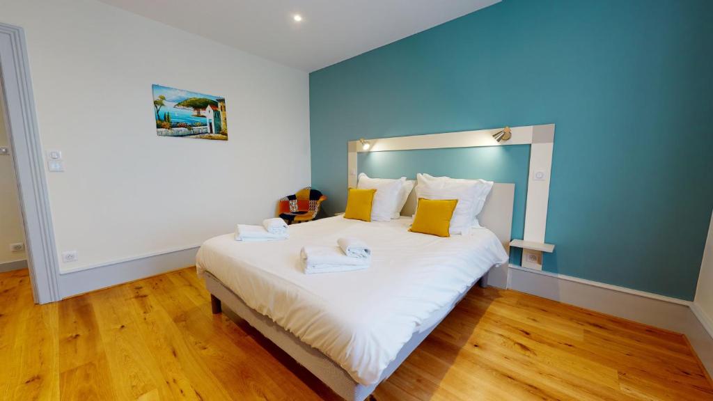 - une chambre avec un grand lit blanc et des oreillers jaunes dans l'établissement Le Muguet 3 chambres - 1 GARAGE GRATUIT, à Colmar