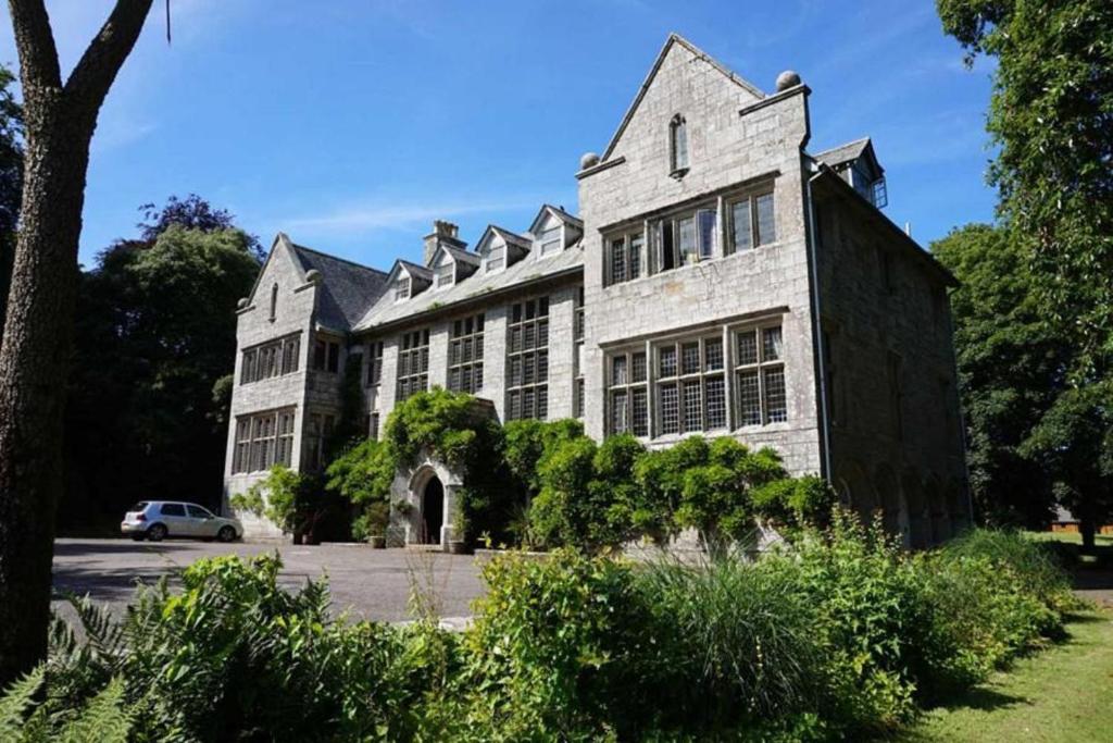 un gran edificio blanco con un coche aparcado delante de él en Hengar Manor Apartments, en Michaelstow