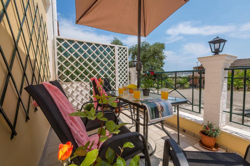 un patio con mesa, sillas y sombrilla en Borts apartment, en Corfú