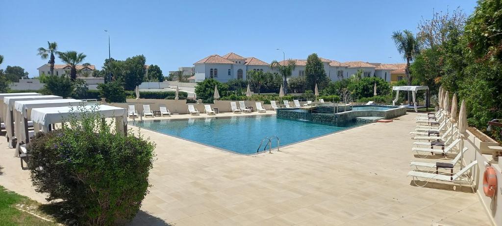 a large swimming pool with lounge chairs and a swimming pool at E-Hotel Larnaca Resort & Spa in Larnaka