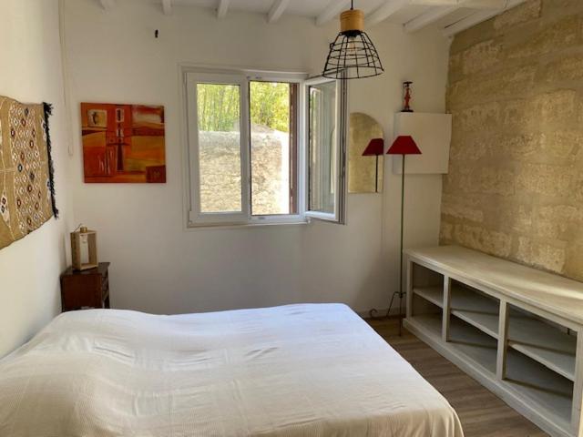 ein Schlafzimmer mit einem weißen Bett und einem Fenster in der Unterkunft Charmant studio à 2 pas du centre historique in Sommières