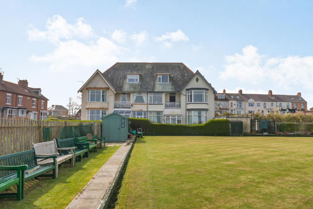a large house with two green benches in a yard at Beachside Apartment in Hornsea