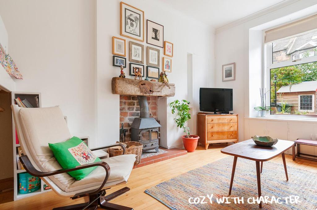 a living room with a chair and a fireplace at Cozy with Character Vibrant Cottage Style Flat at Leith Links Park in Edinburgh