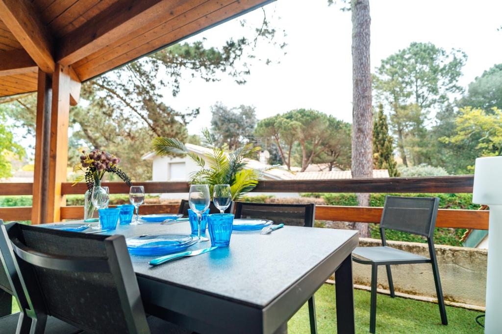 - une table et des chaises sur une terrasse couverte offrant une vue sur l'extérieur dans l'établissement LA FORESTIERE - Petit havre de paix au Pyla, face aux pins, à La Teste-de-Buch