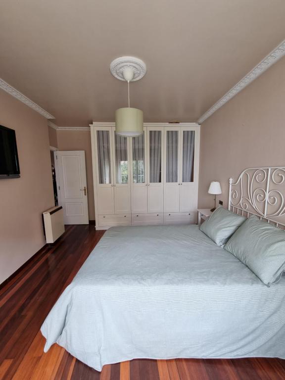 a bedroom with a large white bed with a chandelier at Piso de 3 habitaciones a 3 minutos de la playa. in Ribeira