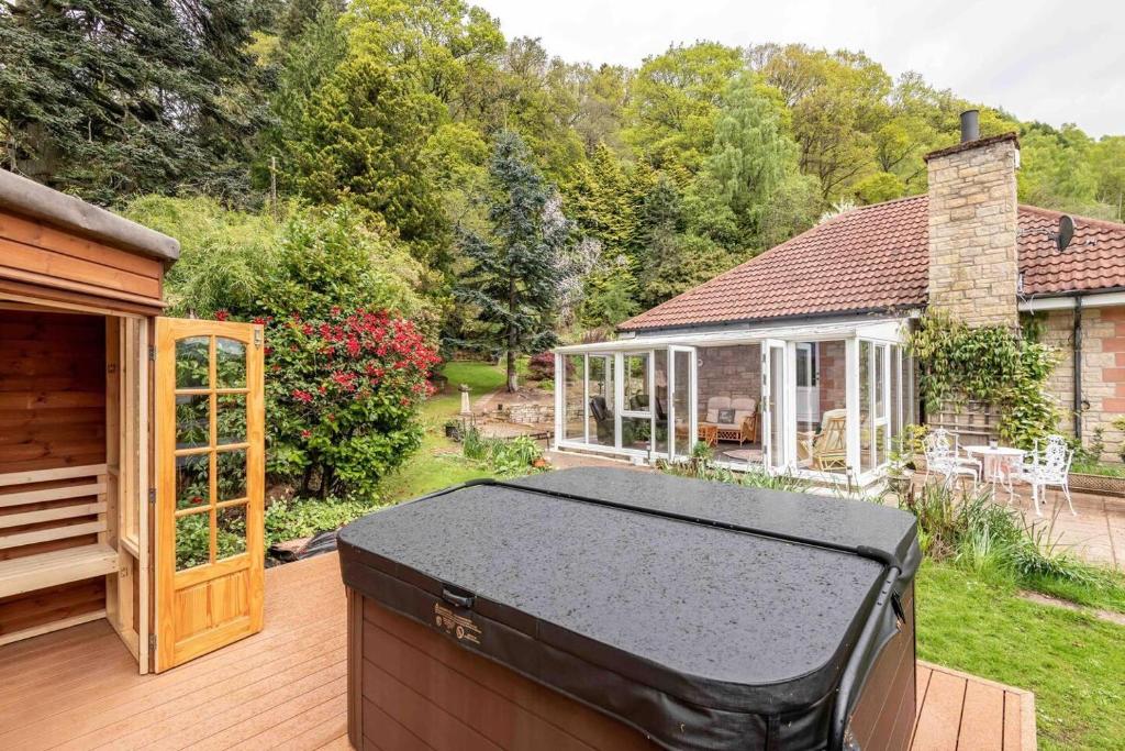 a backyard with a grill on a wooden deck at 3 bedroom bungalow with htub & private loch access in Crieff