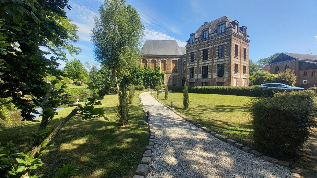 a building with a walkway in front of a yard at Château de Ruesnes in Ruesnes