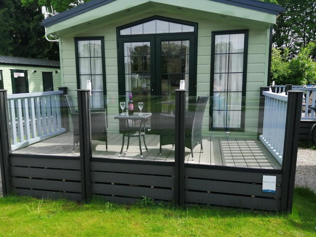 a house with a deck with a table on it at No1 Borwick Lakes in Carnforth