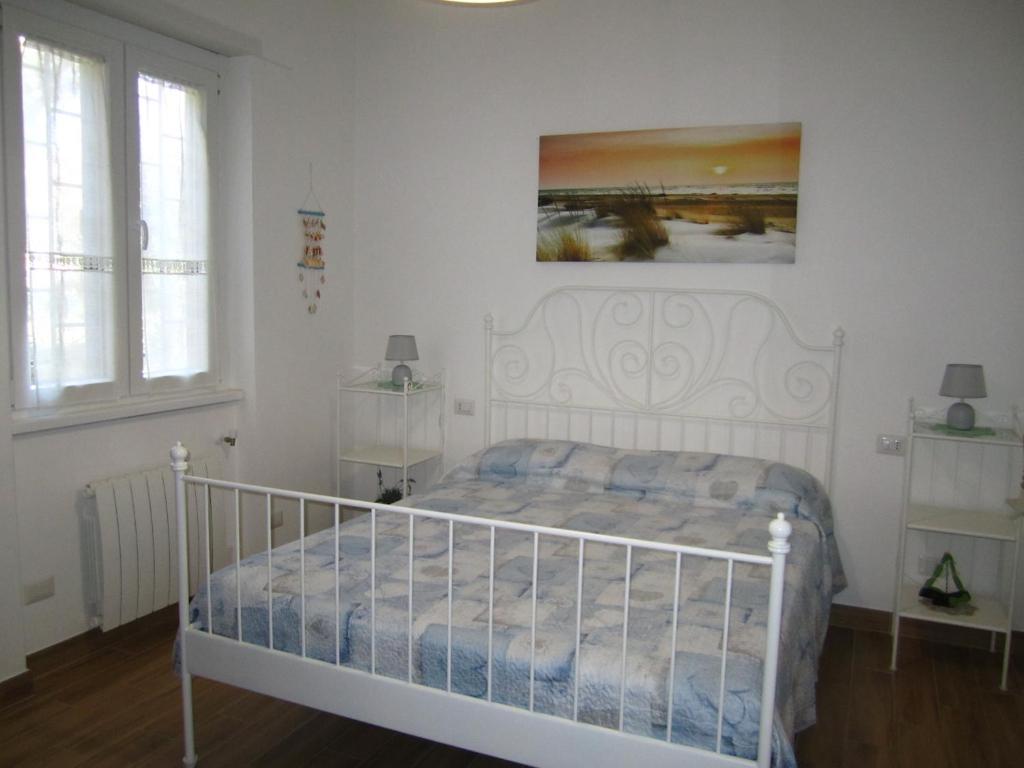 a bedroom with a white bed with a painting on the wall at Casa Casella, delizioso bilocale a due passi dal mare in Lido di Ostia