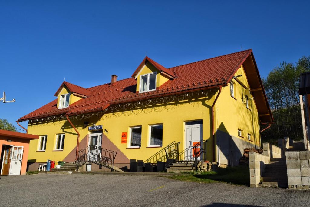 a yellow house with a red roof on a street at Penzión na Hranici Čirč in Čirč