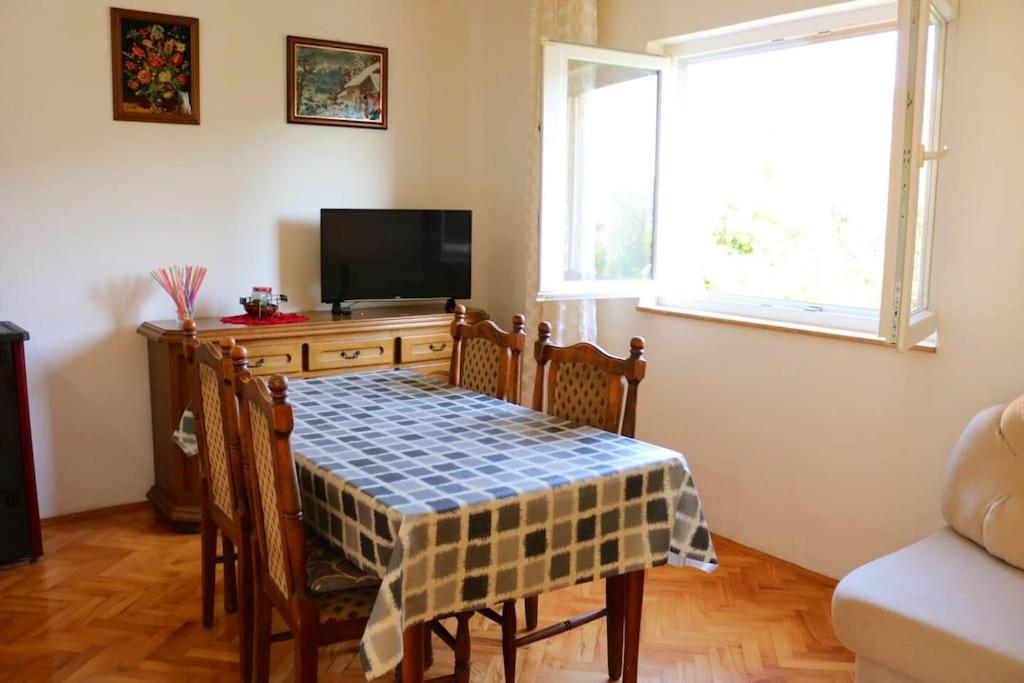 a dining room with a table and a tv at Olive apartments in Grebaštica