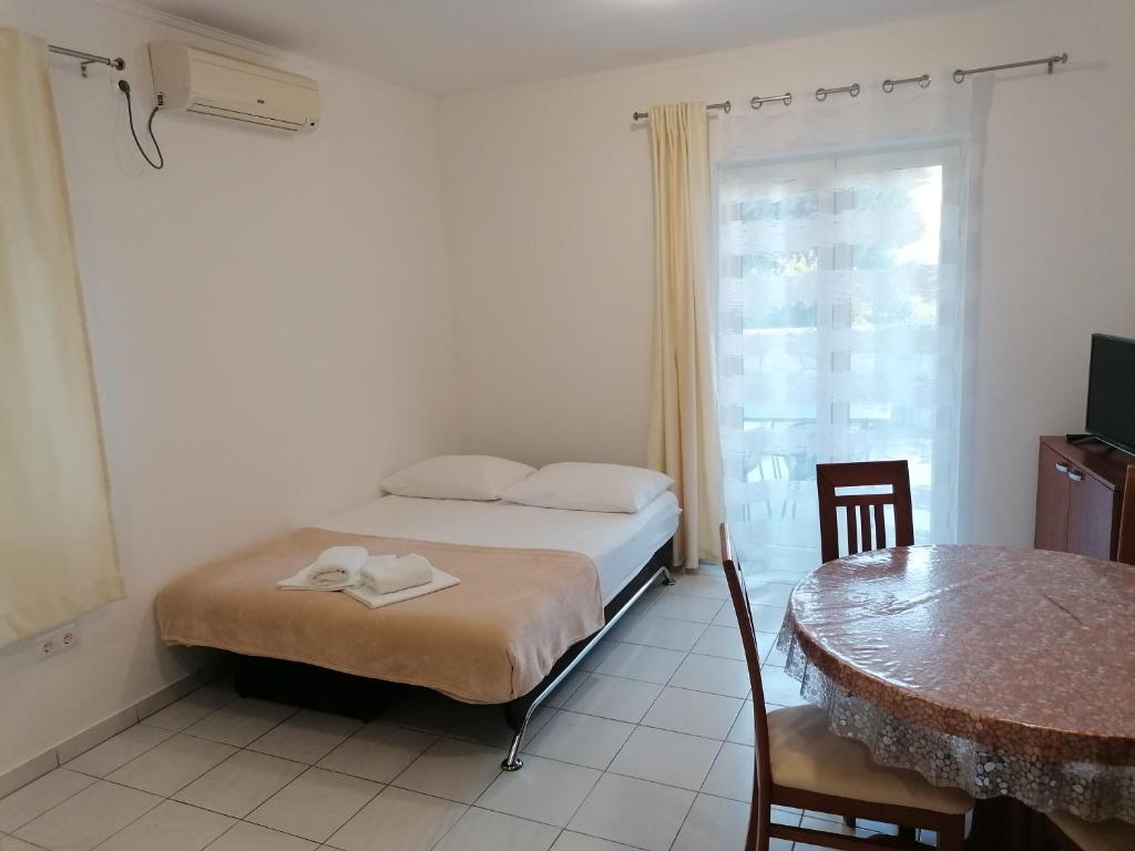 a bedroom with a bed and a table and a window at Apartments Dinko in Duće