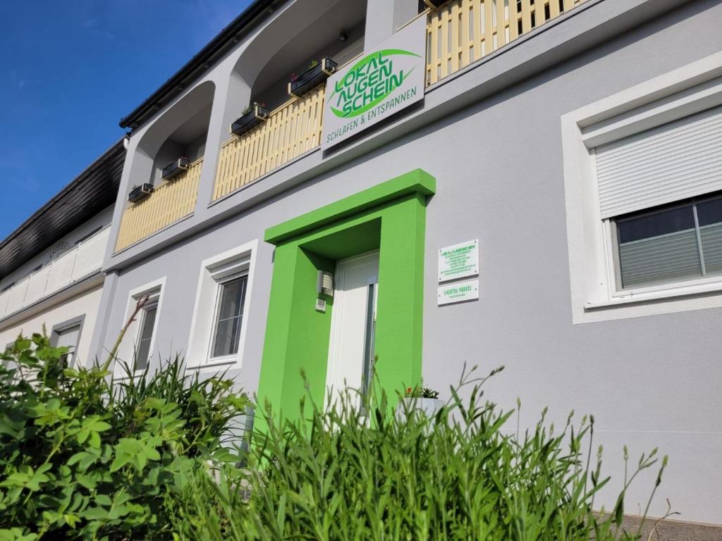 un edificio con una puerta verde y un balcón en Gästehaus Lokalaugenschein, en Podersdorf am See