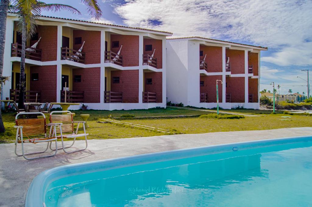 a resort with a swimming pool in front of a building at Pousada Varanda da Praia in Conceição da Barra