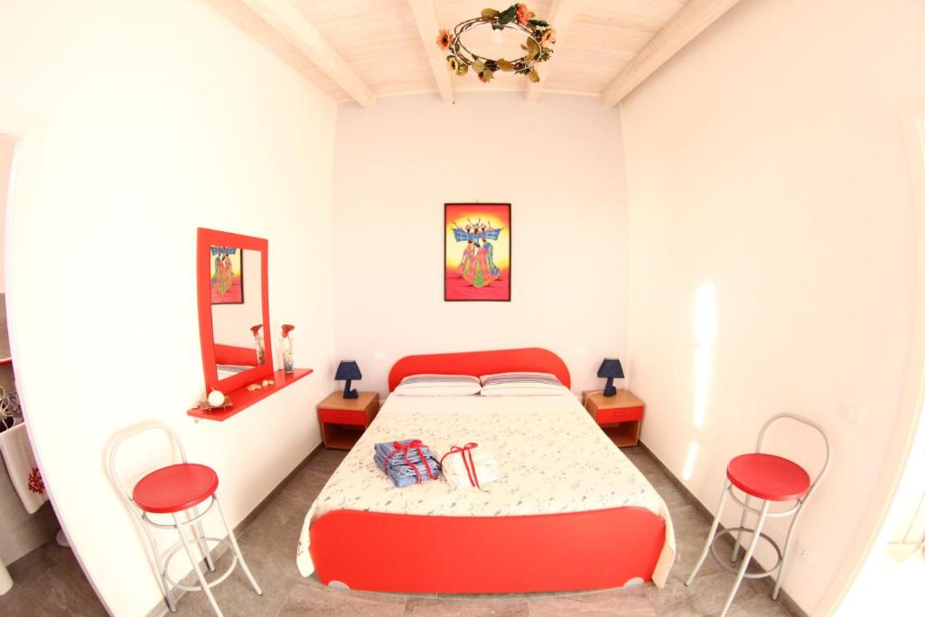 1 dormitorio con 1 cama y 2 sillas rojas en IL CIELO IN UNA STANZA, en Balestrate