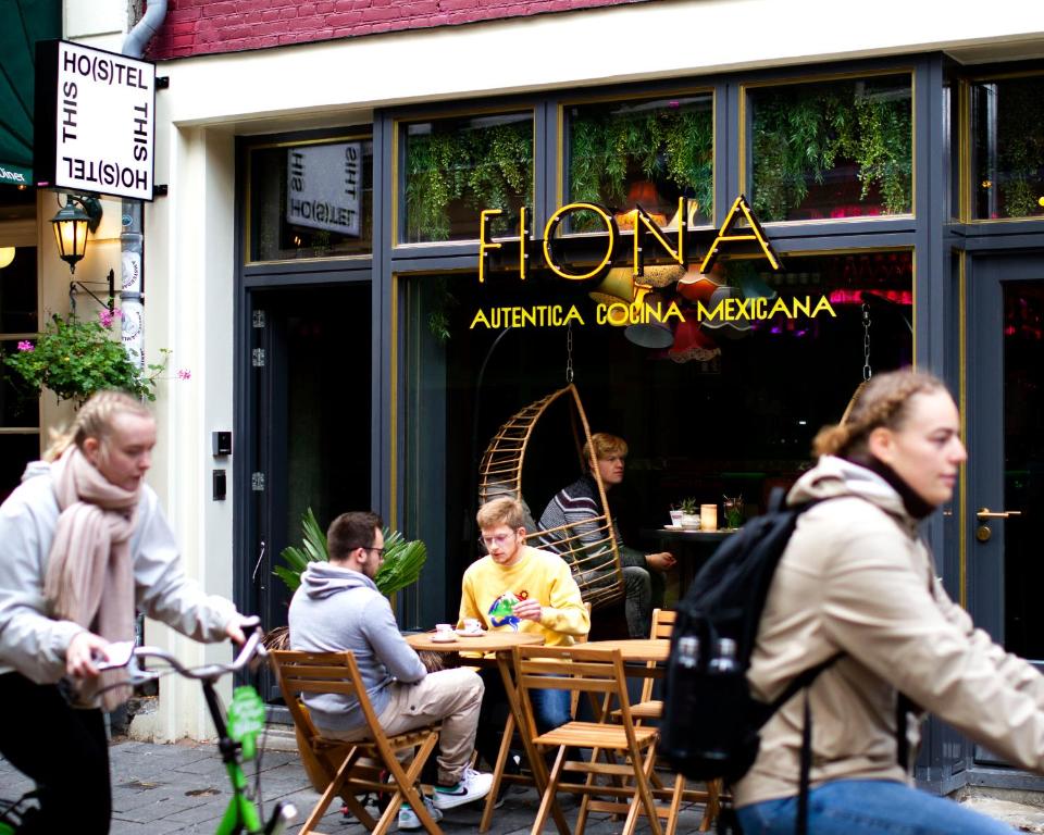 eine Gruppe von Personen, die vor einem Restaurant an einem Tisch sitzen in der Unterkunft THIS HO(S)TEL in Amsterdam