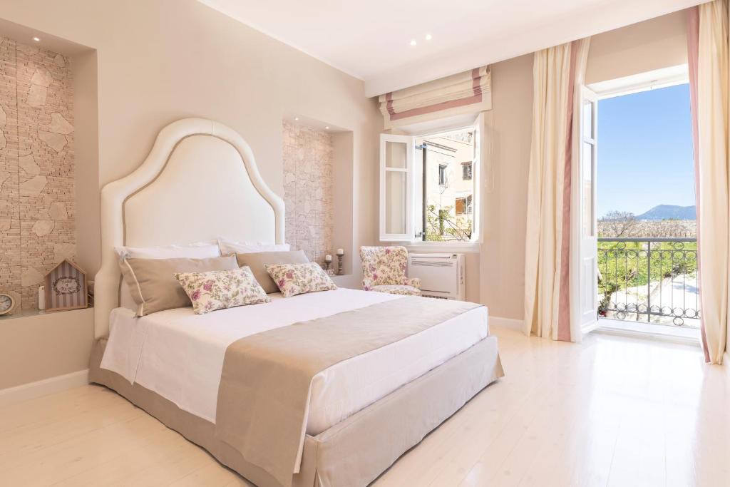 1 dormitorio blanco con 1 cama grande y ventana grande en Stemma Veneziano, en Corfú