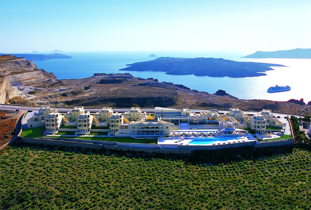 a large building with a pool in front of the ocean at The Majestic Hotel in Fira