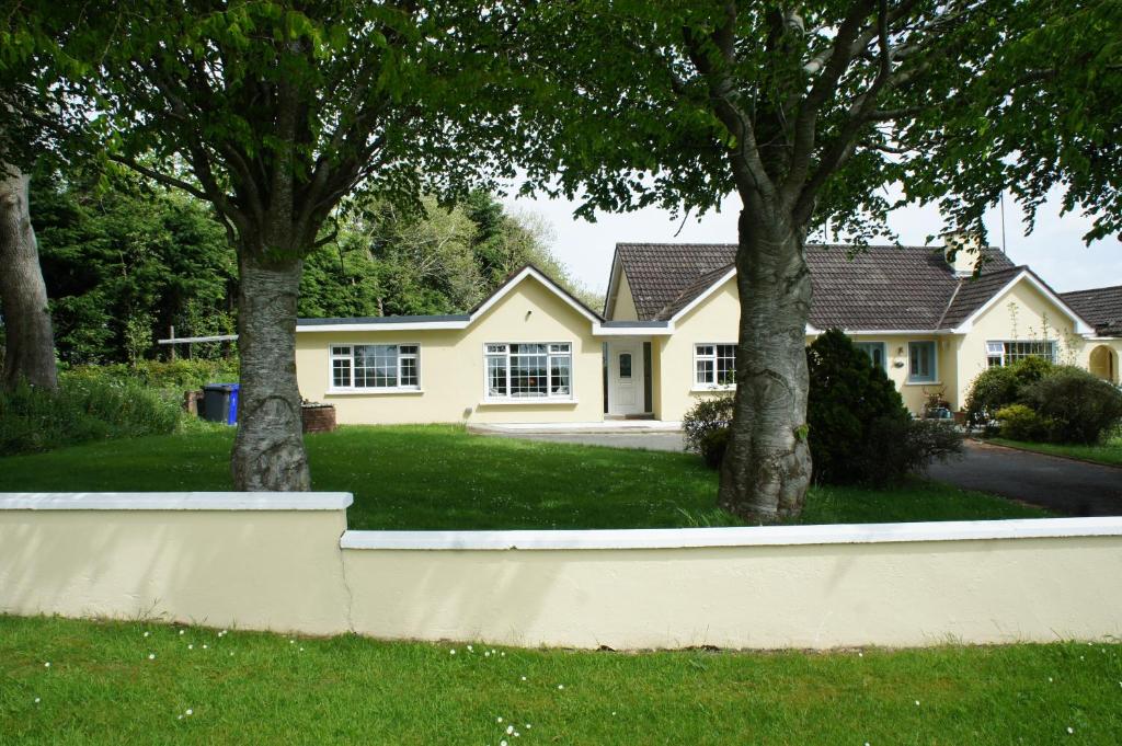 a yellow house with two trees in the yard at Brownstead Cottage in Navan