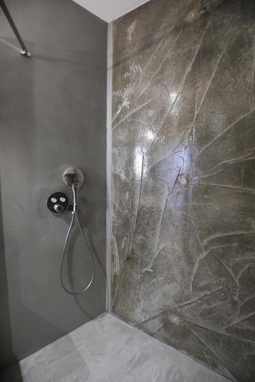 a shower in a bathroom with a stone wall at Hôtel confidentiel Le Grecale in Pianottoli-Caldarello