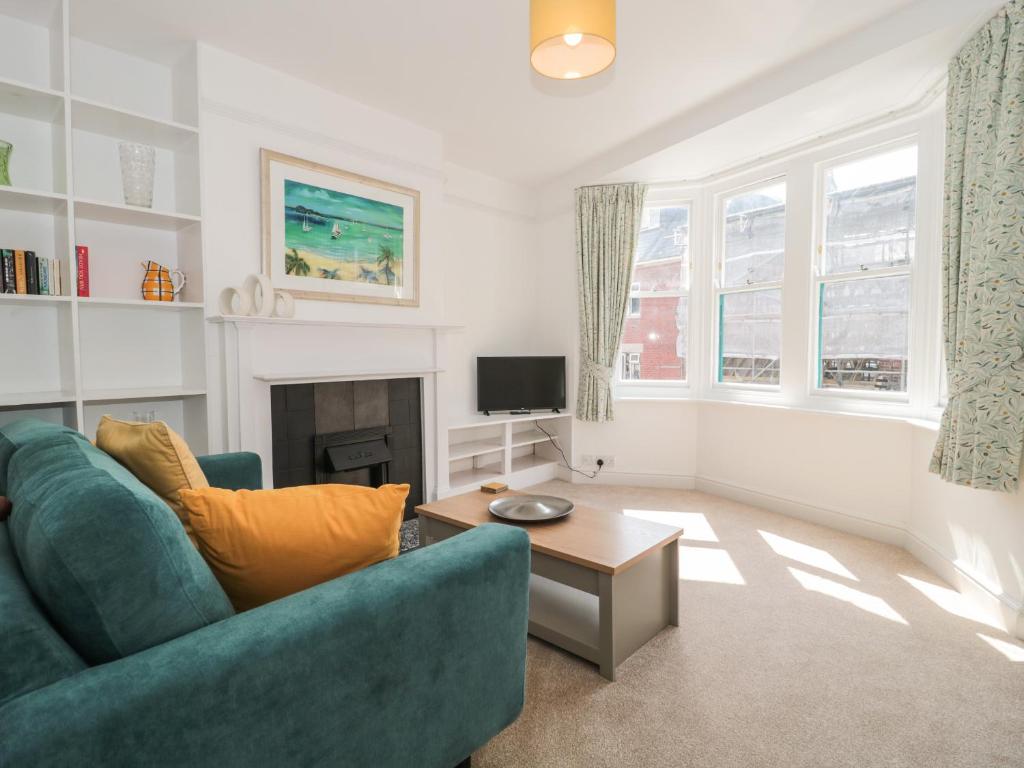 a living room with a blue couch and a tv at Bluebell Apartment in Swanage