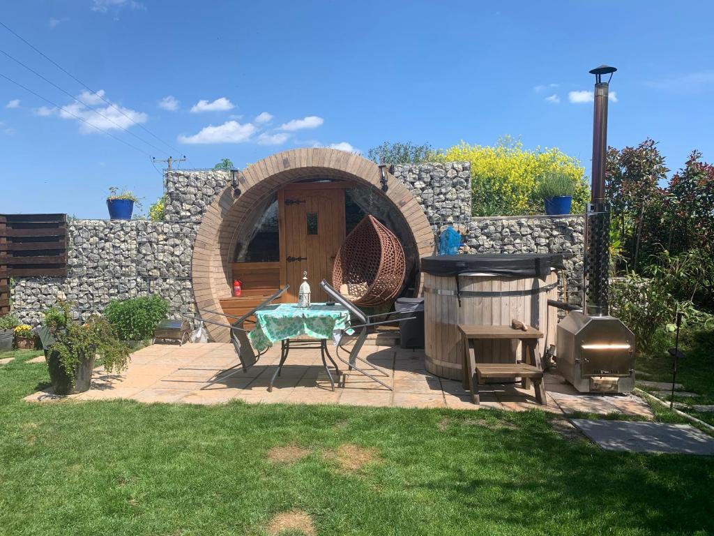 um pátio com uma mesa e um grelhador num quintal em Romantic escape luxury hobbit house with hot tub em Sheerness