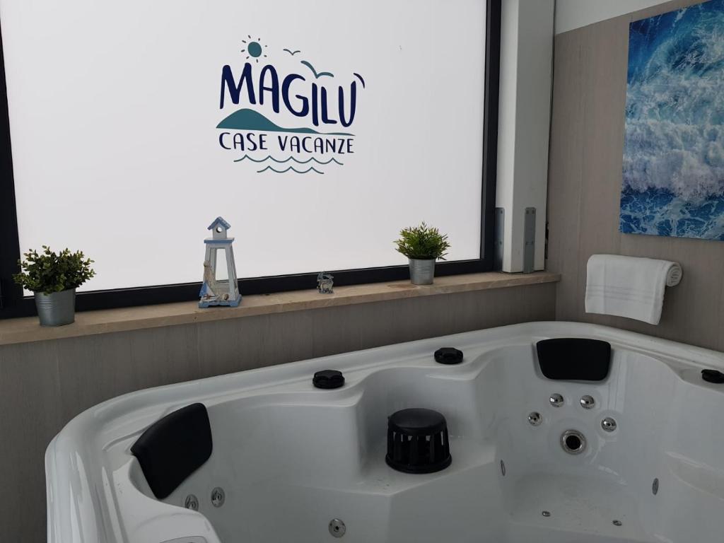 a white bath tub in a bathroom with a large window at Magilù Case con Jacuzzi in Castellammare del Golfo