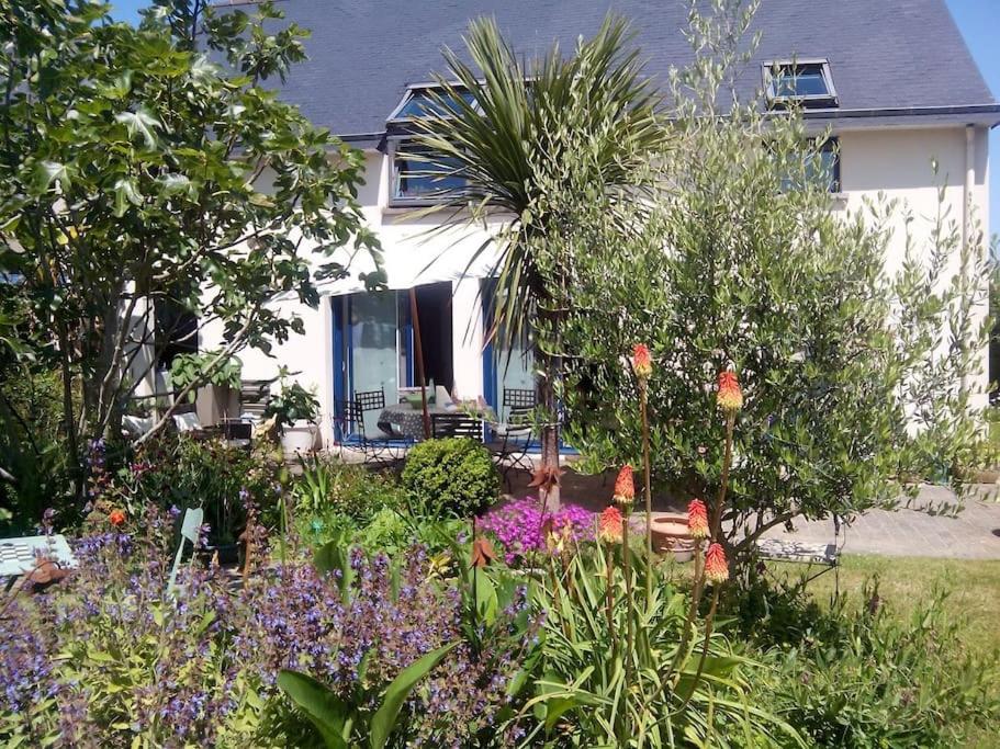 un jardin avec des fleurs en face d'une maison dans l'établissement Maison familiale sur la CÔTE D’ÉMERAUDE, à Lancieux