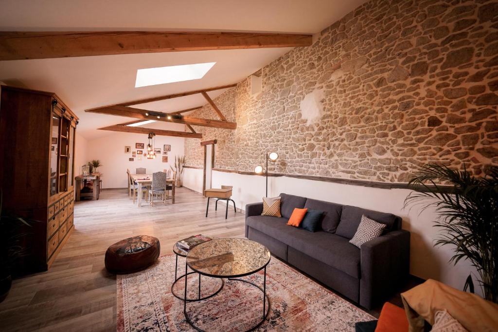 een woonkamer met een bank en een tafel bij Proche PuyDuFou - Gite Maison La Roulière in Saint-Aubin-de-Baubigné