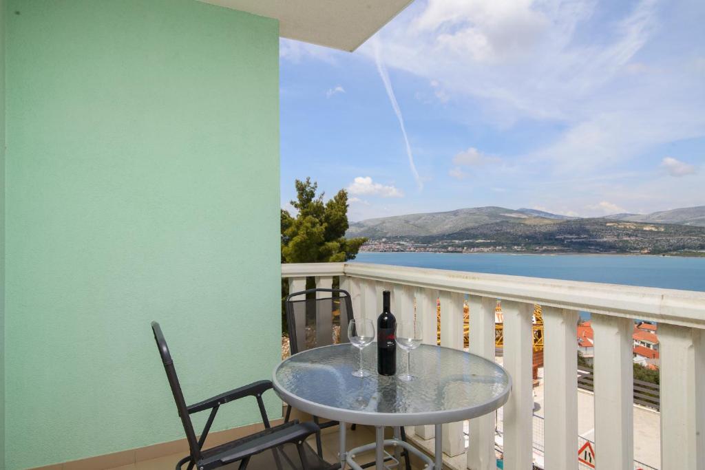 een tafel en stoelen op een balkon met uitzicht op het water bij Apartman Karla in Trogir