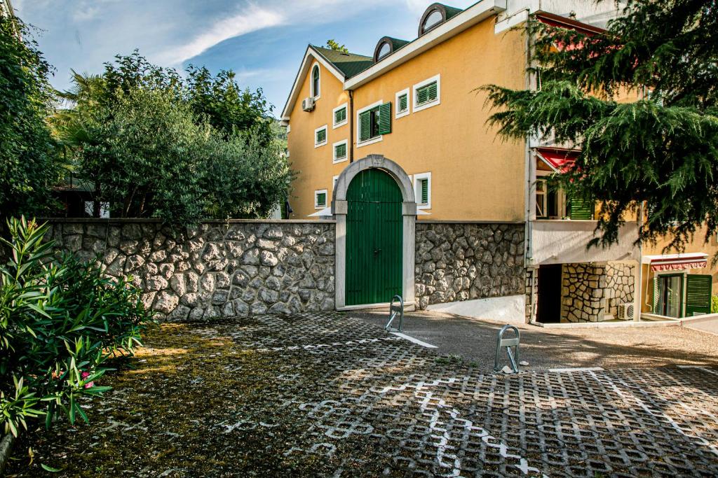 a building with a green door and a stone wall at Villa Beller New in Ičići