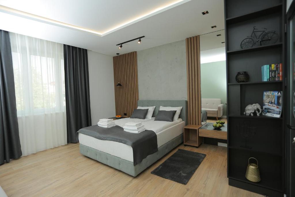 1 dormitorio con 1 cama extragrande y espejo en Bonanza Apartments, en Niš