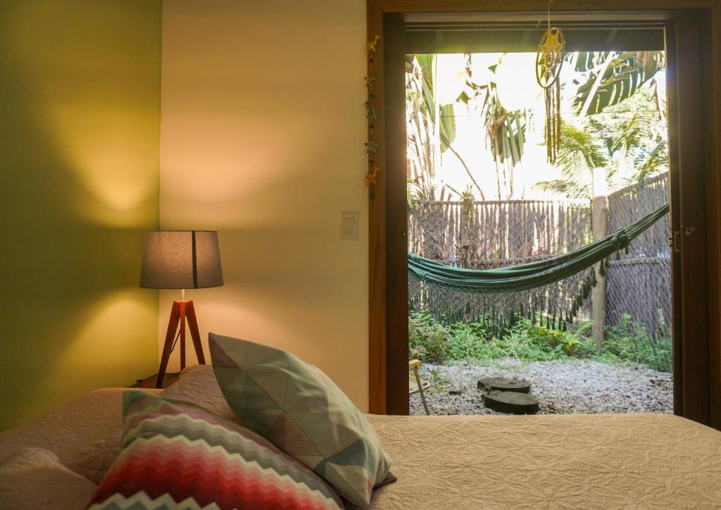 a bedroom with a bed and a window with a hammock at Casa Viva Itamambuca in Ubatuba