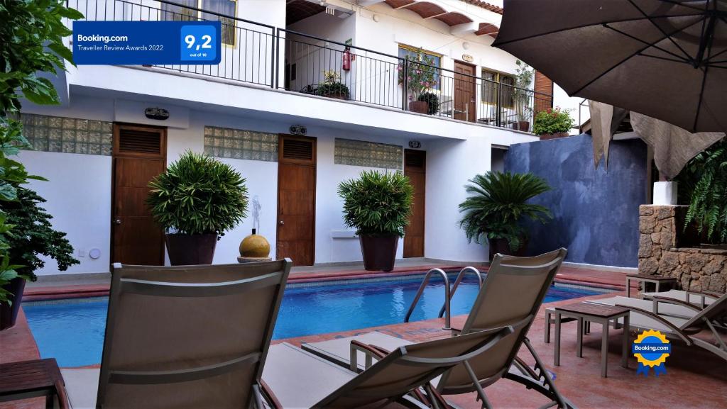 a swimming pool with chairs and a table and an umbrella at Hotel Diamante Sayulita in Sayulita