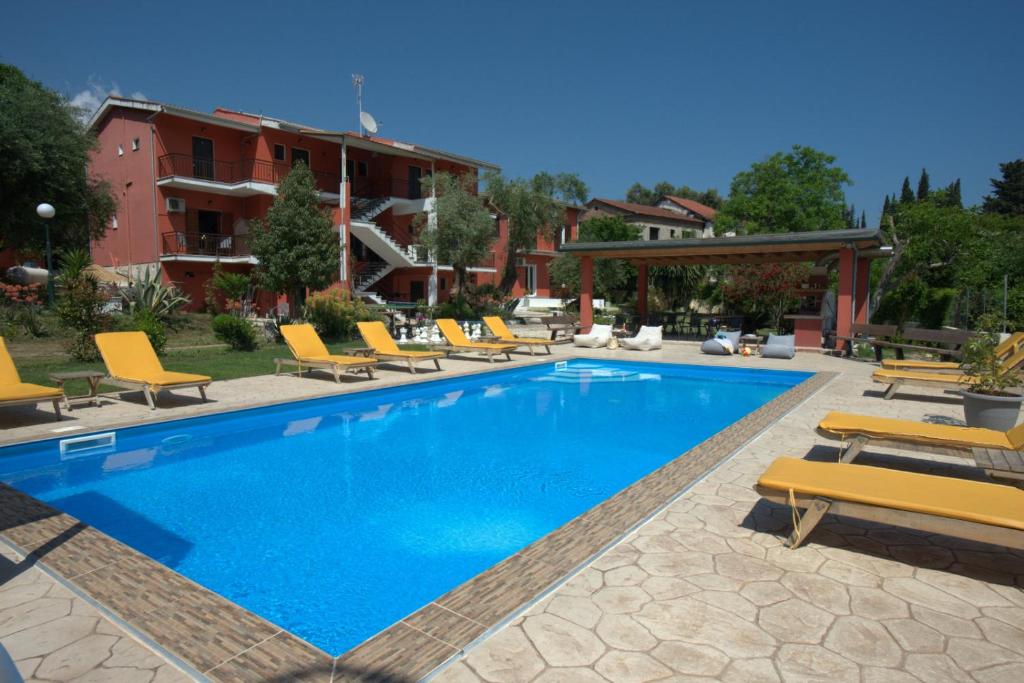 a swimming pool with lounge chairs and a hotel at Ilias Apartments in Ipsos