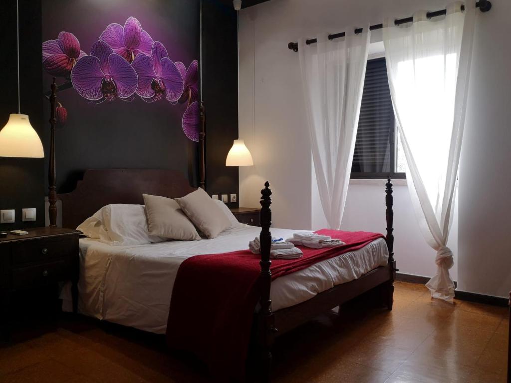 a bedroom with a bed with purple flowers on the wall at Zen Museu do Bonsai in Sintra