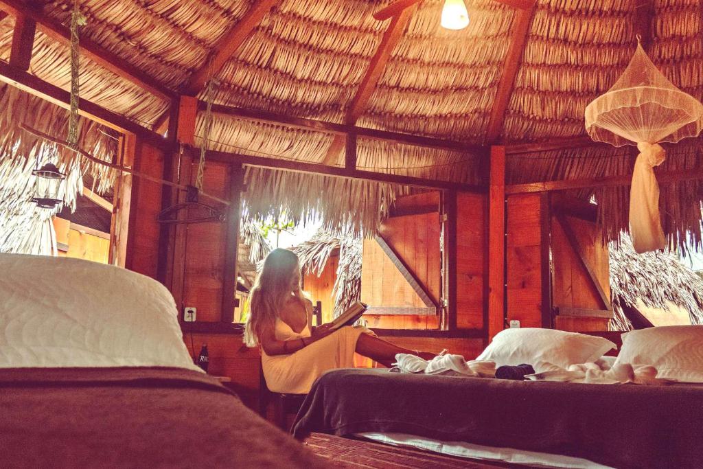 uma mulher sentada num quarto com duas camas em Raiz Kite Cabana em Jericoacoara