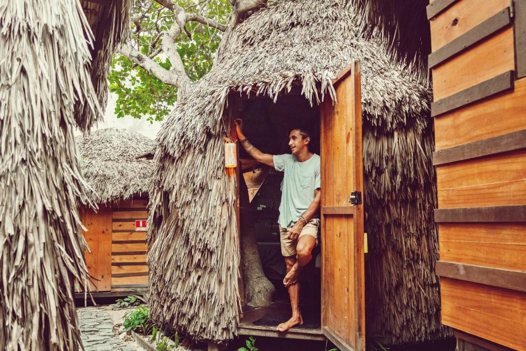 a man standing in the doorway of a thatched house at Raiz Kite Cabana in Jericoacoara